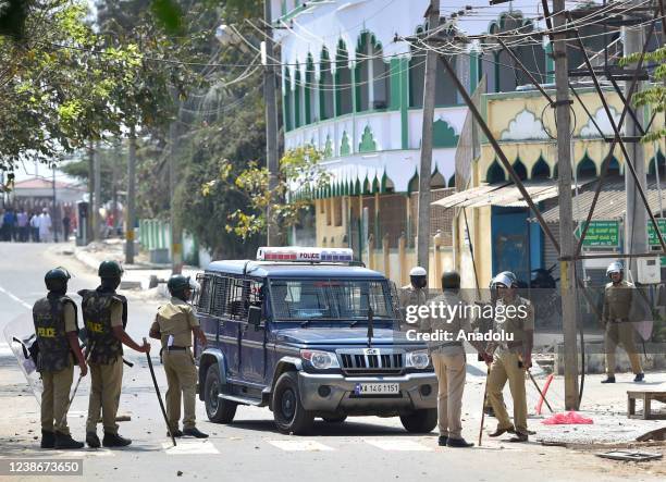 Police personnel guard a mosque as rioters start pelting stones, as tension spreads in Shivamogga town over the murder of a member of right-wing...