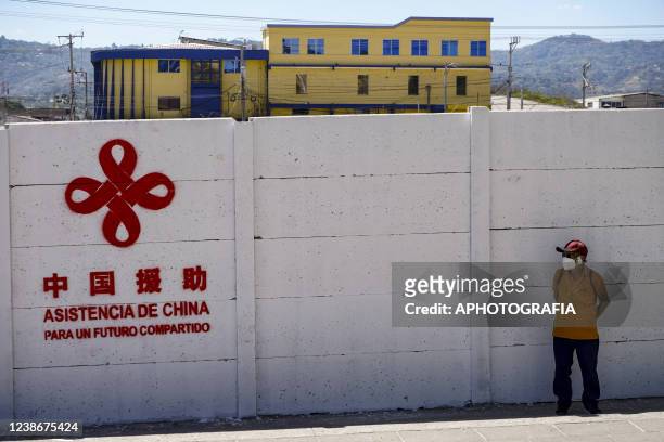 Man wearing a protective mask covers from the sun next to a China AID mural as the constructions of the new Salvadoran National Library begins on...