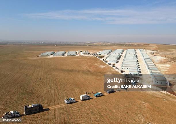 This picture shows an aerial view of internally displaced Syrians arriving with their belongings in a convoy of trucks, at a new housing complex in...