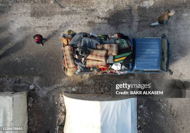 This aerial view shows internally displaced Syrians loading their belongings onto a truck at a camp, before being transported to a new housing...