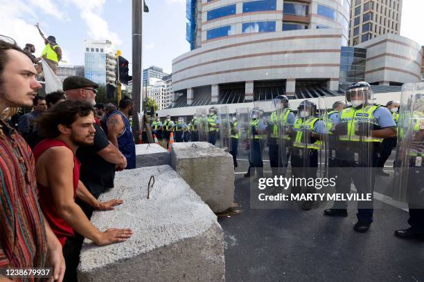 Riot police form a line in front of the parliament building in Wellington on February 22 as anti-vaccine demonstrators occupy the streets and grounds...