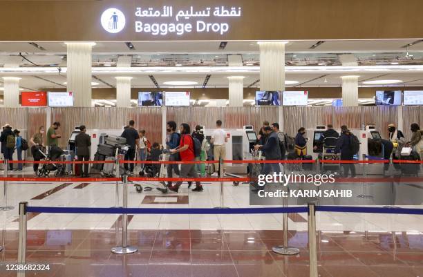 Travellers wait with their luggage at the check-in counter at Dubai International Airport on February 21, 2022. - Passenger traffic at Dubai...