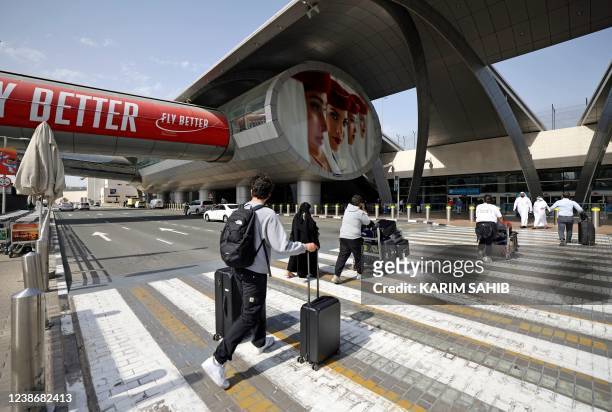 Travellers arrive with their luggage outside Dubai International Airport on February 21, 2022. - Passenger traffic at Dubai international airport,...