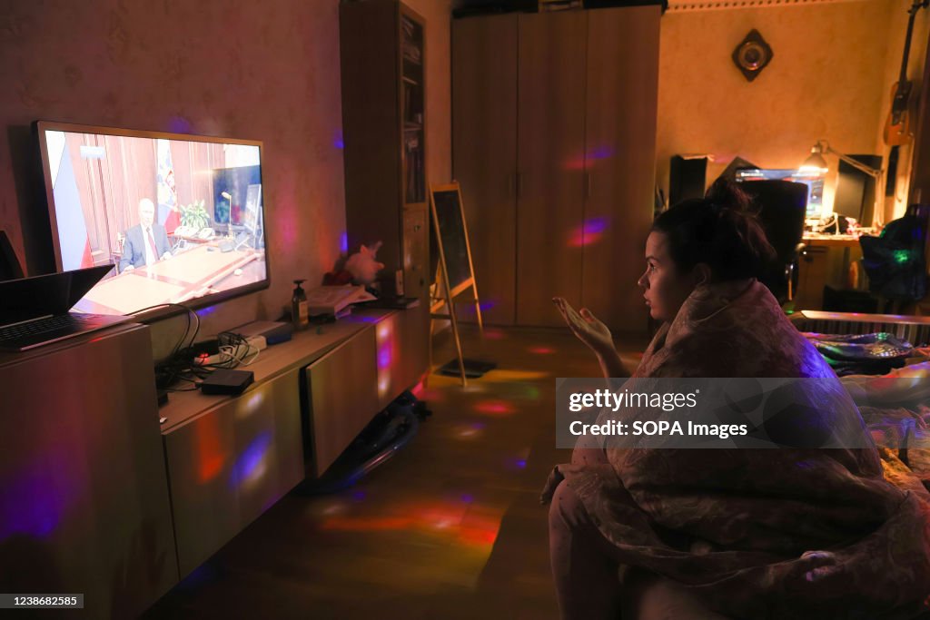A woman watches TV with Russian President Vladimir Putin...