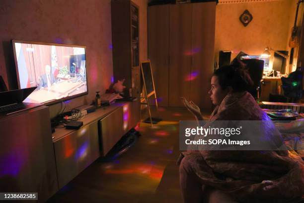 Woman watches TV with Russian President Vladimir Putin speaking during a broadcast after a meeting with the National Security Council to recognize...
