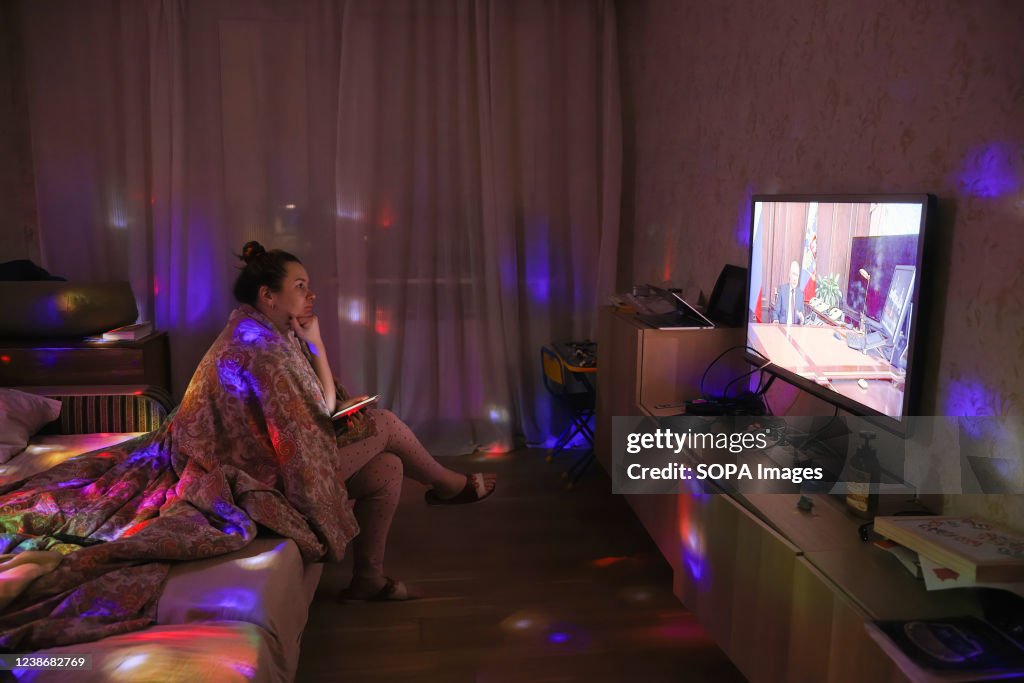 A woman watches TV with Russian President Vladimir Putin...