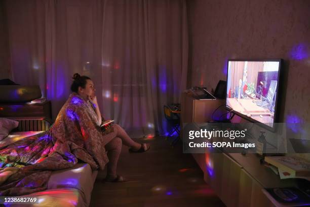 Woman watches TV with Russian President Vladimir Putin speaking during a broadcast after a meeting with the National Security Council to recognize...
