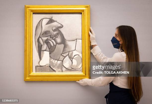 Gallery assistant poses with an artwork entitled 'Buste de femme accoudee' by Spanish artist Pablo Picasso, during a photocall ahead of a sale of...