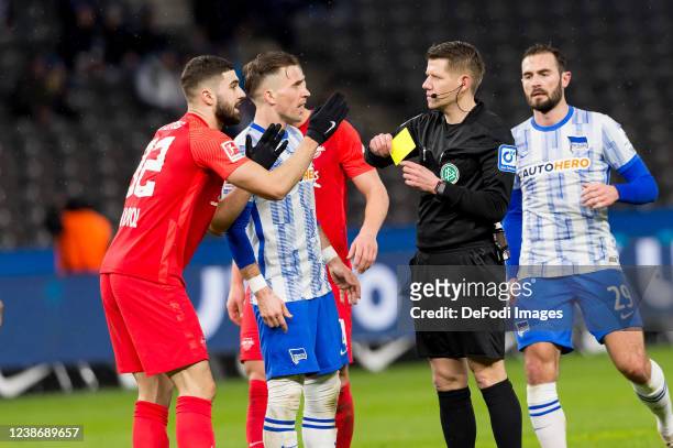 Referee Patrick Ittrich shows Josko Gvardiol of RB Leipzig the yellow card during the Bundesliga match between Hertha BSC and RB Leipzig at...