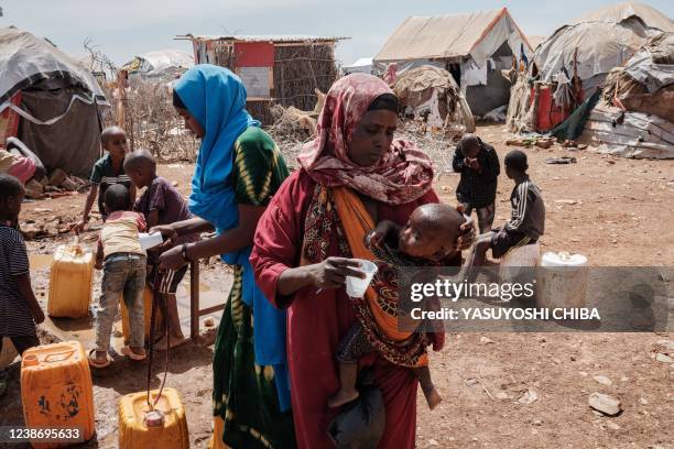 Bulley Hassanow Alliyow gives water to her child at Tawkal 2 Dinsoor camp for internally displaced persons in Baidoa, Somalia, on February 14, 2022....