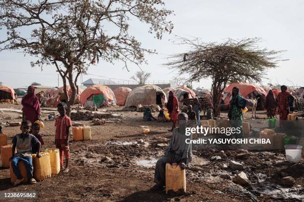 People wait for water with containers at a camp, one of the 500 camps for internally displaced persons in town, in Baidoa, Somalia, on February 13,...