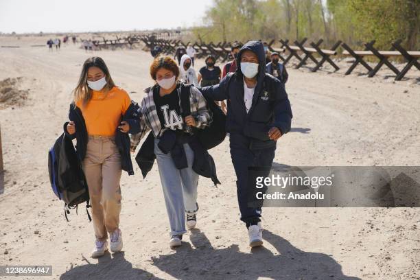 Asylum seeking migrants from Colombia, Cuba, and Venezuela arrive on US soil, after crossing the Colorado River, from Mexico on February 21, 2022 in...