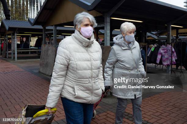 Two elderly women, both wearing face masks to protect against Covid-19, walk through market stalls in Kirkgate Market on 22nd February, 2022 in...