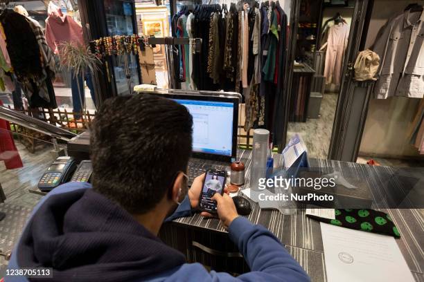 An Iranian trader checks the page of his shop on Instagram while sitting at his shop in a shopping center in northern Tehran on February 23, 2022....