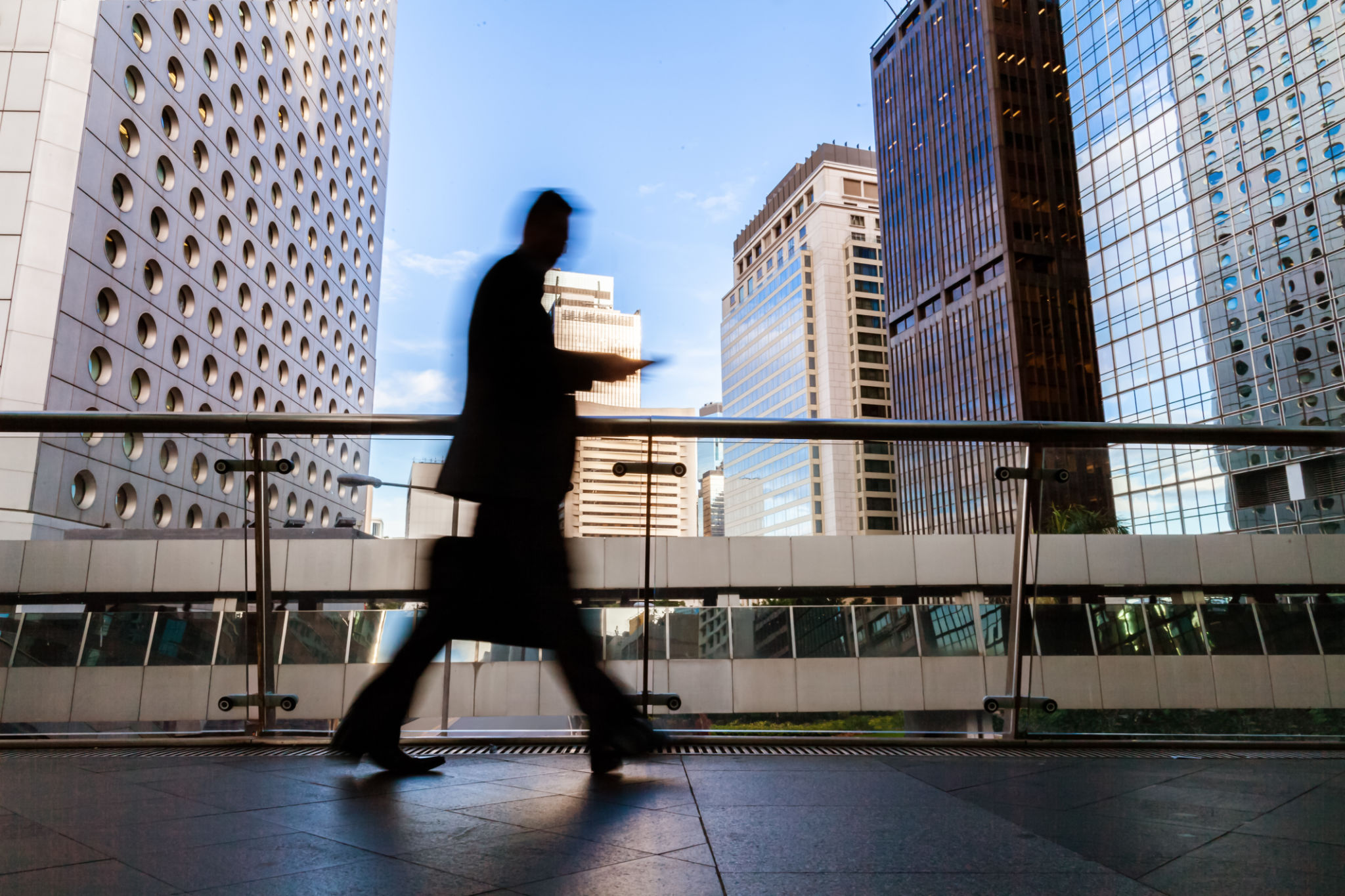 Blurred motion silhouette of businessman walking in Hong Kong’s Central District elevated walkway Blurred motion silhouette of businessman walking in Hong Kong’s Central District elevated walkway