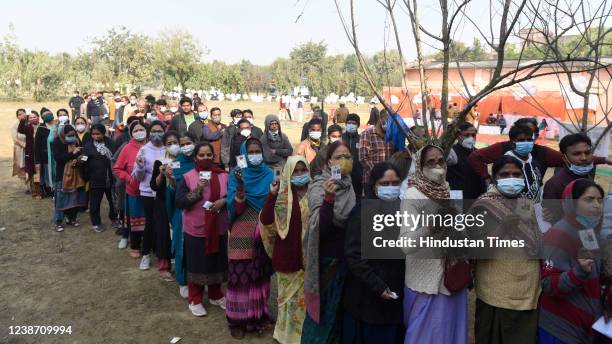 Voters show their identity cards as they stand in queues to cast their votes at Sanskrit Pathshala polling station during the fourth phase of Uttar...