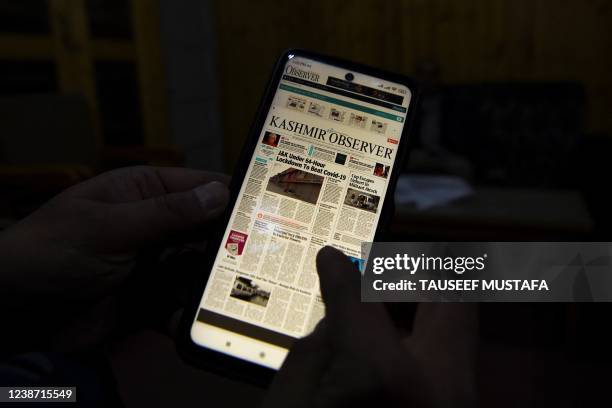 In this photo illustration taken on January 29 a man scrolls through an online version of local news publication Kashmir Observer in Srinagar. - In...