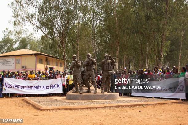 Demonstrators hold a banner reading "We thant the FACA " in Bangui on February 23, 2022 duirng a pro Russia demonstration held around a statue...
