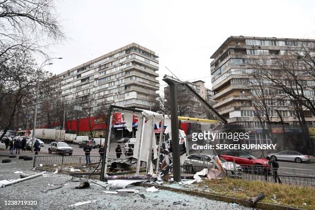 People are seen outside the cordoned off area around the remains of a shell in a street in Kyiv on February 24, 2022. - Russian President Vladimir...