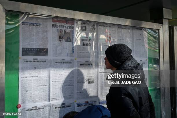 Man reads the Chinese state-run newspaper with coverage of the conflict between Russia and Ukraine, on a street in Beijing on February 24, 2022.