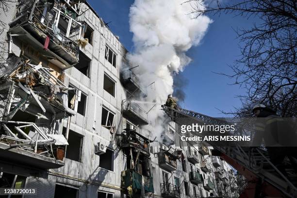 Firefighters work on a fire on a building after bombings on the eastern Ukraine town of Chuguiv on February 24 as Russian armed forces are trying to...