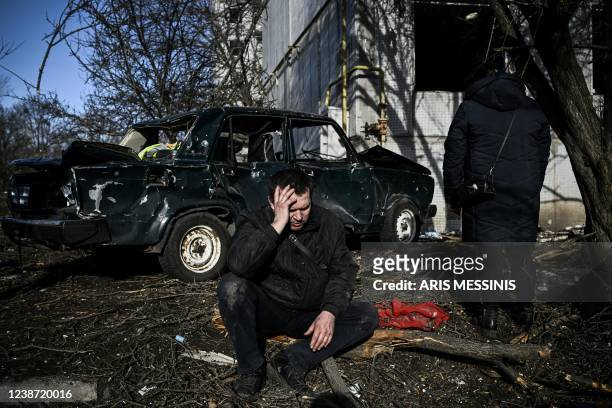 Man sits outside his destroyed building after bombings on the eastern Ukraine town of Chuguiv on February 24 as Russian armed forces are trying to...