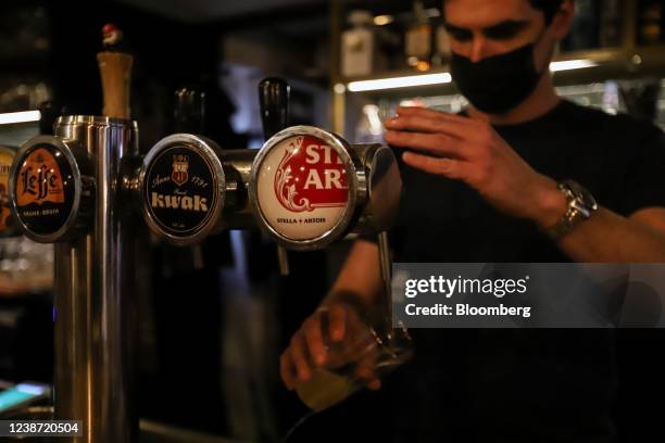 Bartender pours a glass of Stella Artois beer, produced by Anheuser-Busch InBev NV, at a bar in Leuven, Belgium, on Wednesday, Feb. 23, 2022. The...