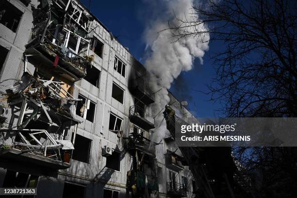 Firefighters work on a fire on a building after bombings on the eastern Ukraine town of Chuguiv on February 24 as Russian armed forces are trying to...