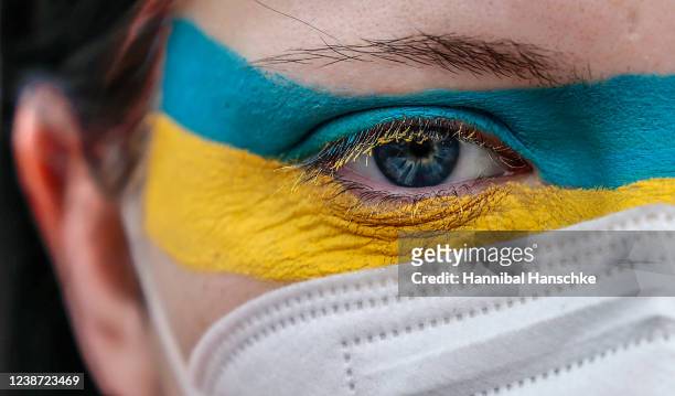Woman wears make up in the colors of the Ukrainian flag protesting against Russian invasion of Ukraine in front of Brandenburg gate on February 24,...