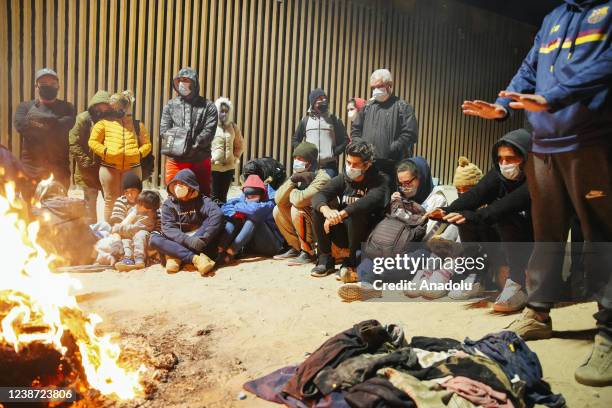 Asylum seekers from Cuba gather around a fire they made out of the items other migrants left behind, such as shoes, clothes, and trash to warm...