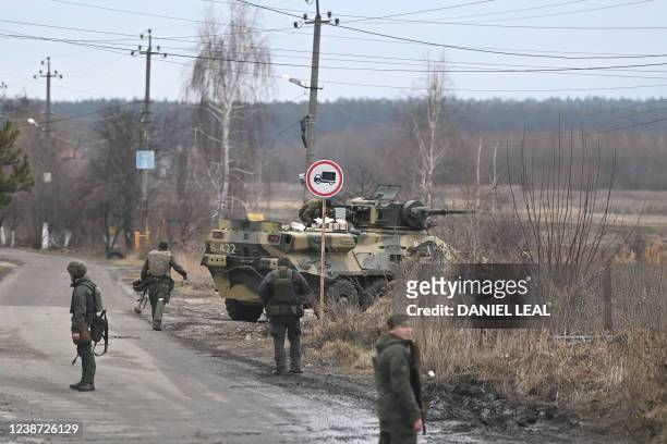 Ukrainian servicemen stand near an armored personnel carrier BTR-3 on the northwest of Kyiv on February 24, 2022. - Ukraine army says battle under...