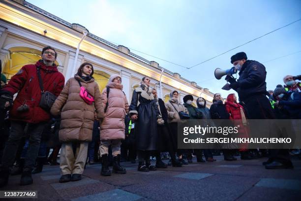 Police officer uses a loudspeaker to address people gathered to protest against Russia's invasion of Ukraine in central Saint Petersburg on February...