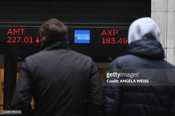 People look at stocks displayed at the New York Stock Exchange at Wall Street on February 24, 2022 in New York. - Wall Street stocks opened sharply...