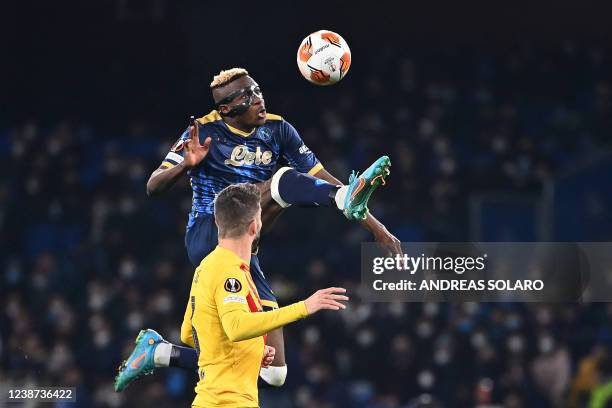 Napoli's Nigerian forward Victor Osimhen jumps for the ball next to Barcelona's Spanish defender Gerard Pique during the UEFA Europa League knockout...