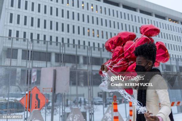 Woman holds heart-shaped balloons before releasing them in front of the US District Court in St Paul, Minnesota, on February 24, 2022. - A jury found...