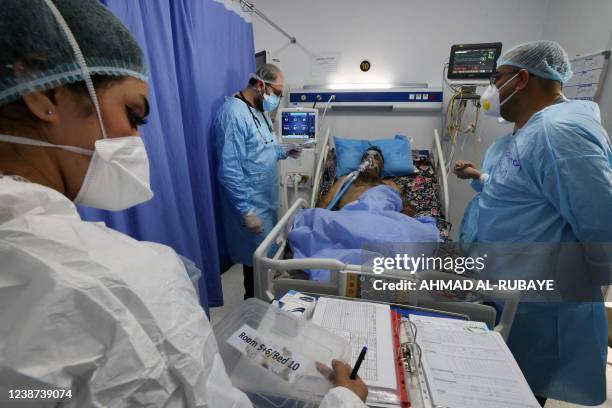 Iraqi medical workers check on a patient at the coronavirus ward of Al-Shifa Hospital in the capital Baghdad, on February 20, 2022. - Half of the 40...