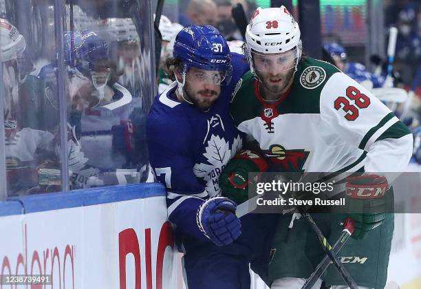 Toronto, ON- February 24 - Toronto Maple Leafs defenseman Timothy Liljegren is checked by Minnesota Wild right wing Ryan Hartman as the Toronto Maple...