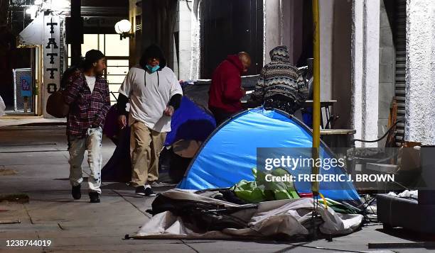 Pedestrians walk past tents housing the homeless on the streets of Los Angeles, California on February 24 as volunteers participate on the third...