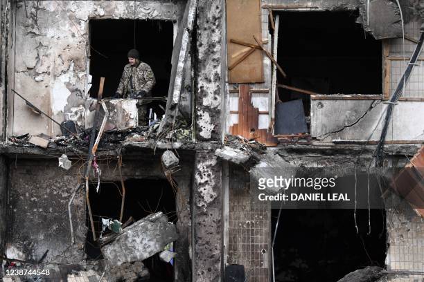 Ukrainian serviceman is seen in the window of a damaged residential building at Koshytsa Street, a suburb of the Ukrainian capital Kyiv, where a...