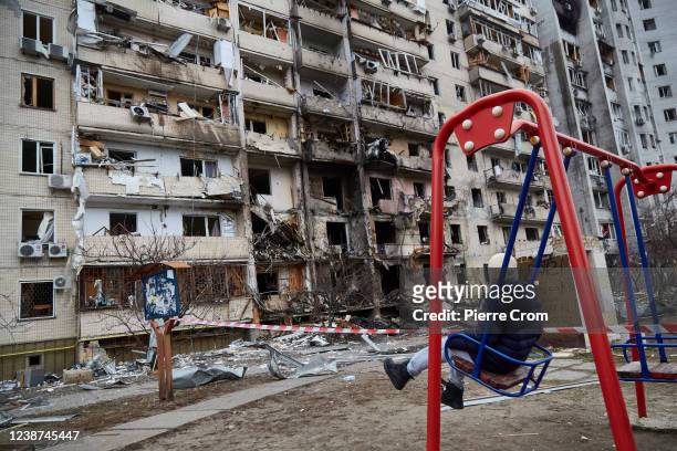 Child on a swing outside a residential building damaged by a missile on February 25, 2022 in Kyiv, Ukraine. Yesterday, Russia began a large-scale...
