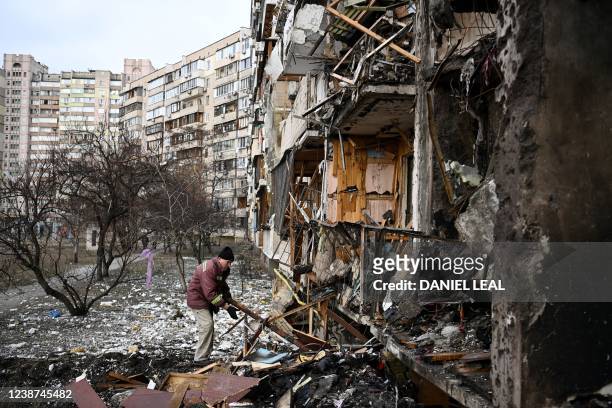 Man clears debris at a damaged residential building at Koshytsa Street, a suburb of the Ukrainian capital Kyiv, where a military shell allegedly hit,...