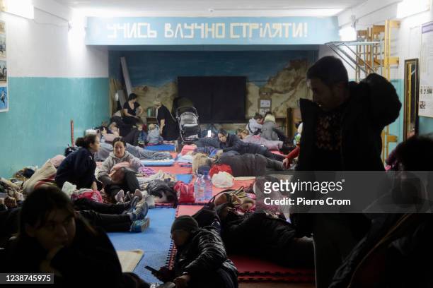 Hundreds of residents from a residential building damaged by a missile gather in a bomb shelter in the basement of a school on February 25, 2022 in...