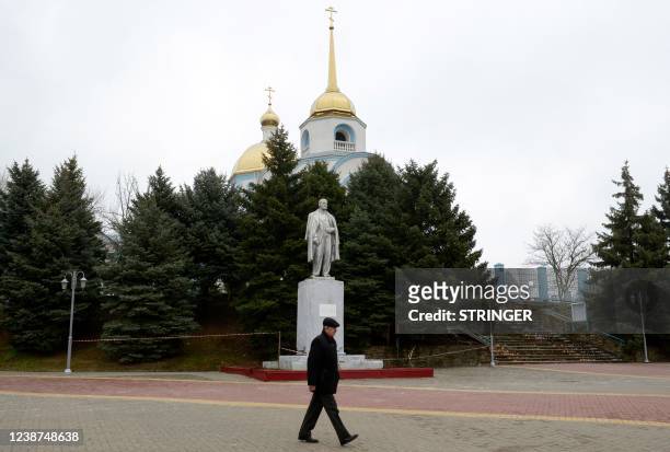 Man walks past a monument to the Soviet state founder Vladimir Lenin and an Orthodox church at a settlement in the southern Russian Rostov region on...