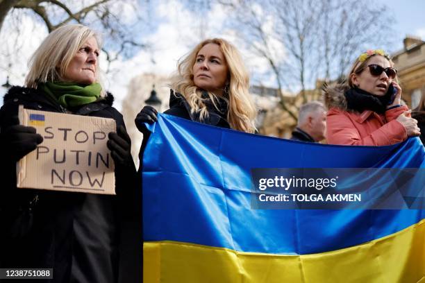 Two demonstrators hold a Ukranian national flag next to a participant carrying a placard reading "Stop Putin now" at a rally staged in front of the...