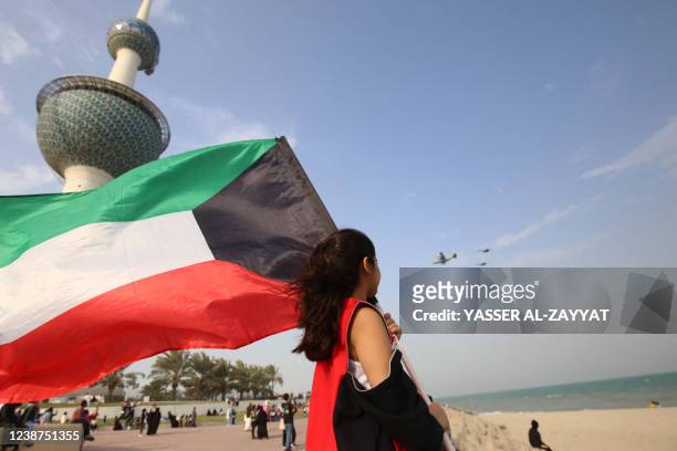 Kuwaiti girl waves the national flag as pilots fly over the Kuwait Towers on February 25 during celebrations of the country's 61st Independence Day...