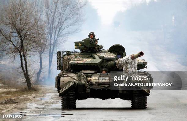Ukrainian servicemen ride on tanks towards the front line with Russian forces in the Lugansk region of Ukraine on February 25, 2022. - Ukrainian...