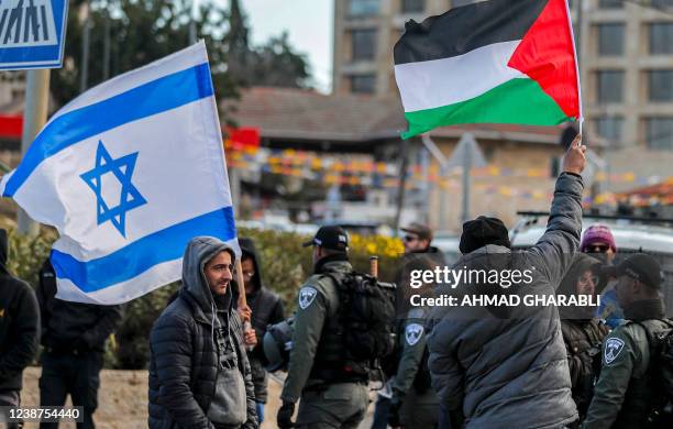 An Israeli settler stands with an Israeli flag before a man holding up a Palestinian flag during a demonstration attended by Palestinians, Israelis,...