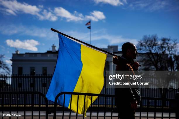 Man with a Ukrainian flag stands on Pennsylvania Avenue in front of the White House as demonstrators gather to protest the Russian invasion on...