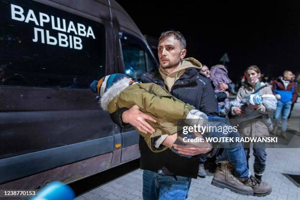 Volunteer carries a child of Ukrainian citizens as they arrive with buses in Przemsyl, eastern Poland, from the Medyka pedestrian border crossing as...