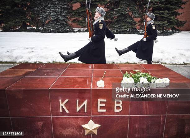Russian honour guard soldiers march past a WWII memorial including a monument "Kyiv - a City Hero" during changing of guards ceremony at the Tomb of...